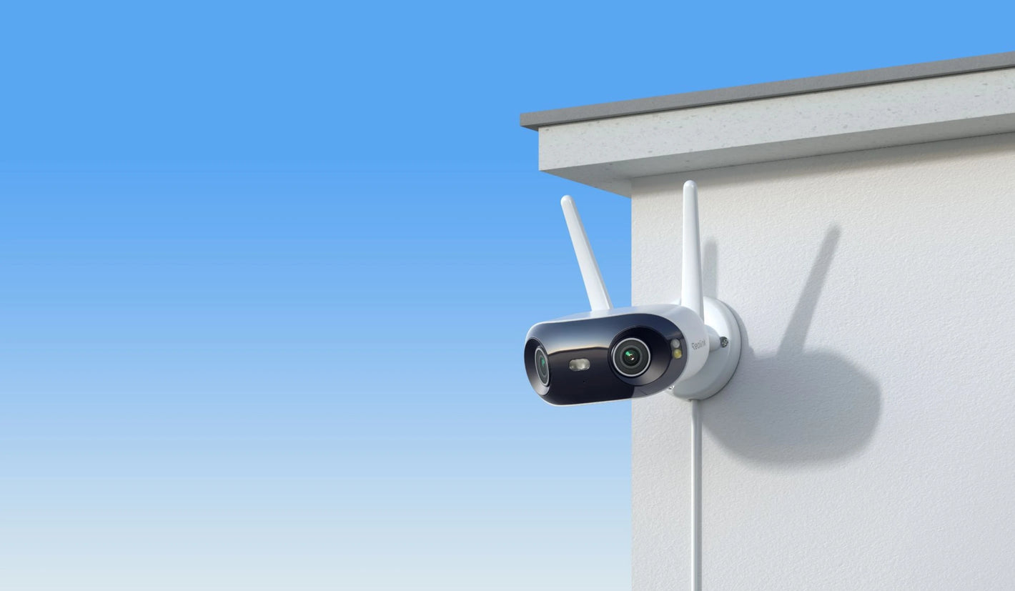 Reolink Elite WIFI Outdoor security camera with antennas attached to a house exterior against a blue sky.