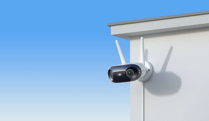 Reolink Elite WIFI Outdoor security camera with antennas attached to a house exterior against a blue sky.