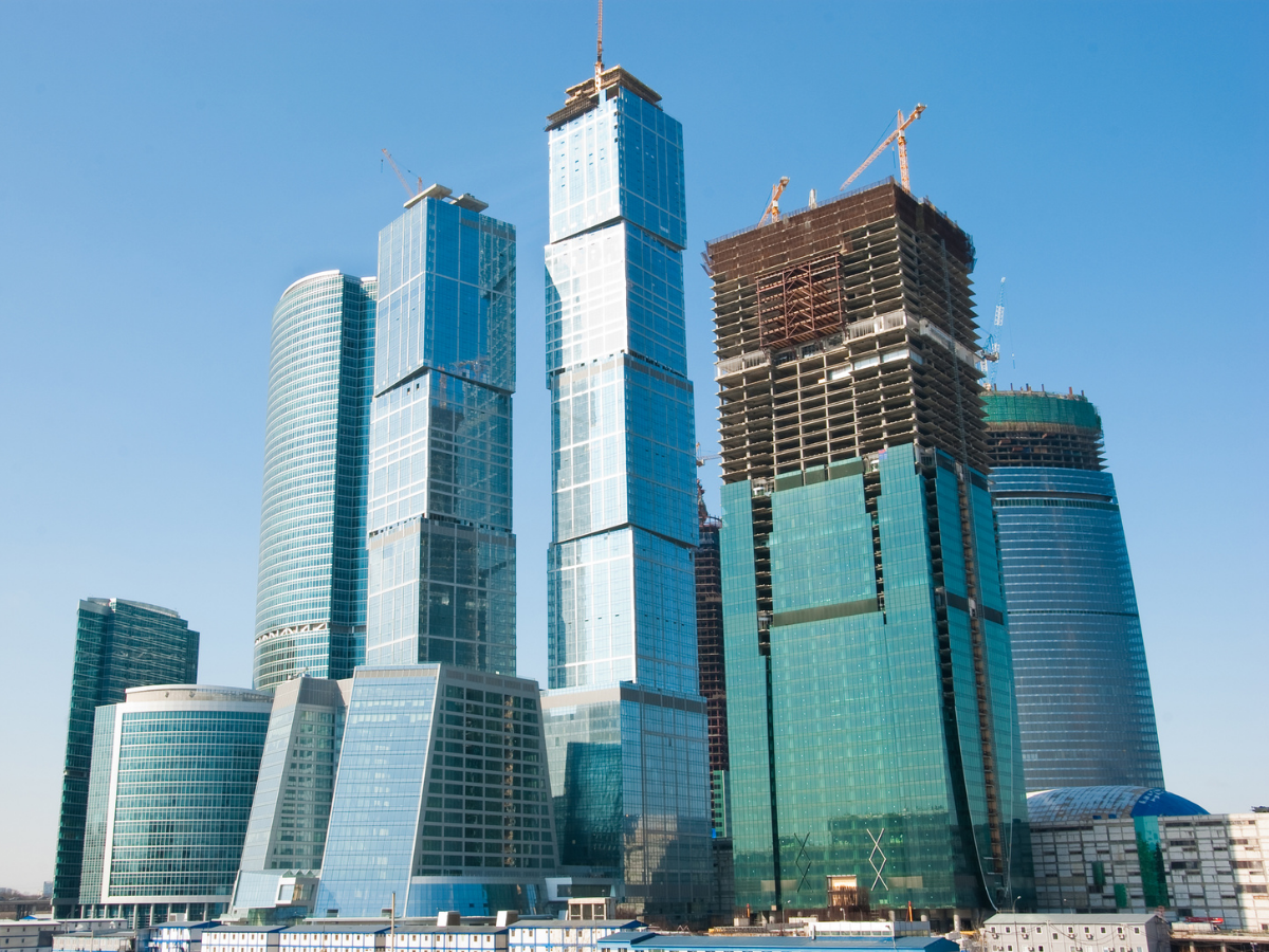 landscape Modern skyscrapers with one under construction against a clear blue sky.