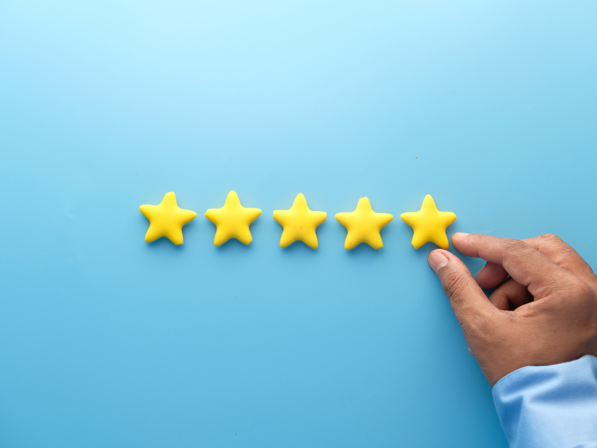 Hand pointing to a five-star rating on a blue background
