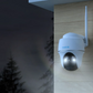 Reolink Argus PT 5MP Wireless Solar Battery Camera with Pan & Tilt on external wall at night emitting white spotlight