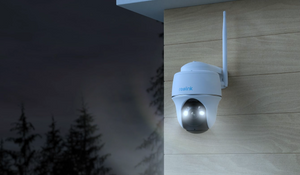 Reolink Argus PT 5MP Wireless Solar Battery Camera with Pan & Tilt on external wall at night emitting white spotlight