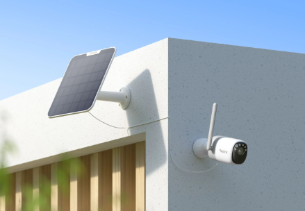Solar panel and reolink altas security camera on a building exterior with clear sky.