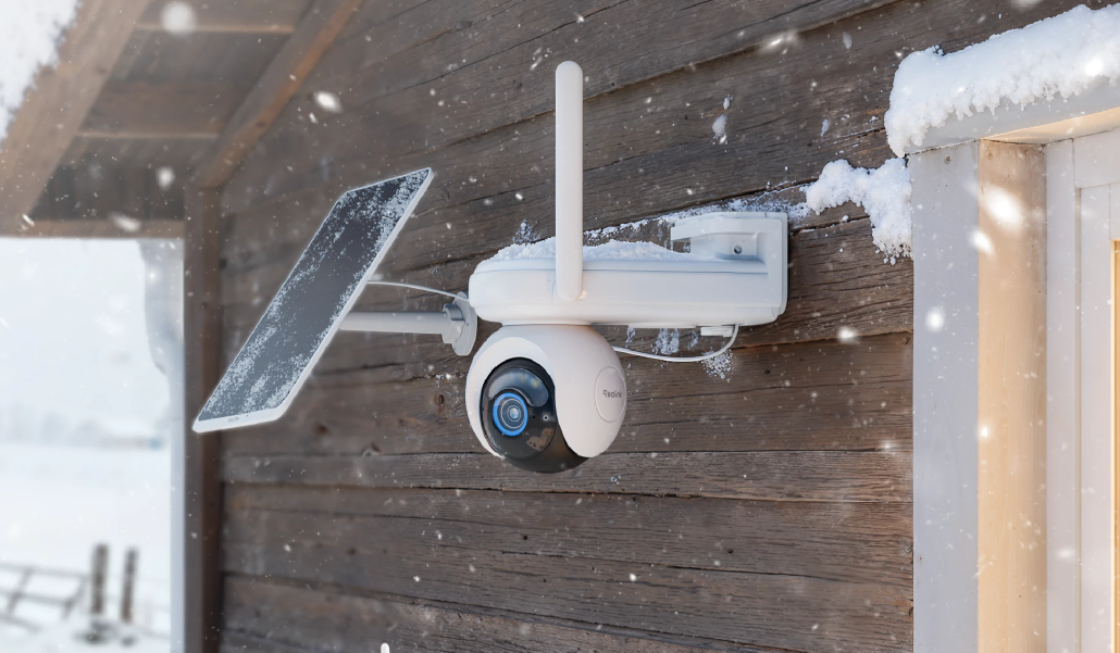 Reolink Altas Go PT Security camera with solar panel on a wooden wall during snowfall