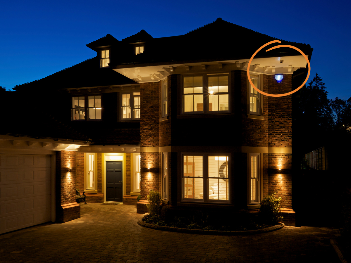 Luxury house exterior at night with a security camera highlighted.
