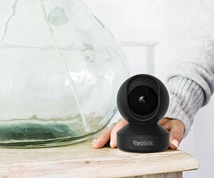 Reolink E1 Pro Just the Right Amount of Everything for Indoor PT Cam on side table next to glass decoration. 